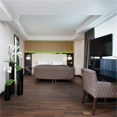 Die Club Suite im Hotel Palace Berlin: Moderner Rückzugsort mit Doppelbett, Schreibtisch, Stuhl und Fernseher. Dekorative Pflanzen und Schwarz-Weiß-Fotografie verleihen Charme, während ein großes Fenster den Raum mit Tageslicht durchflutet.